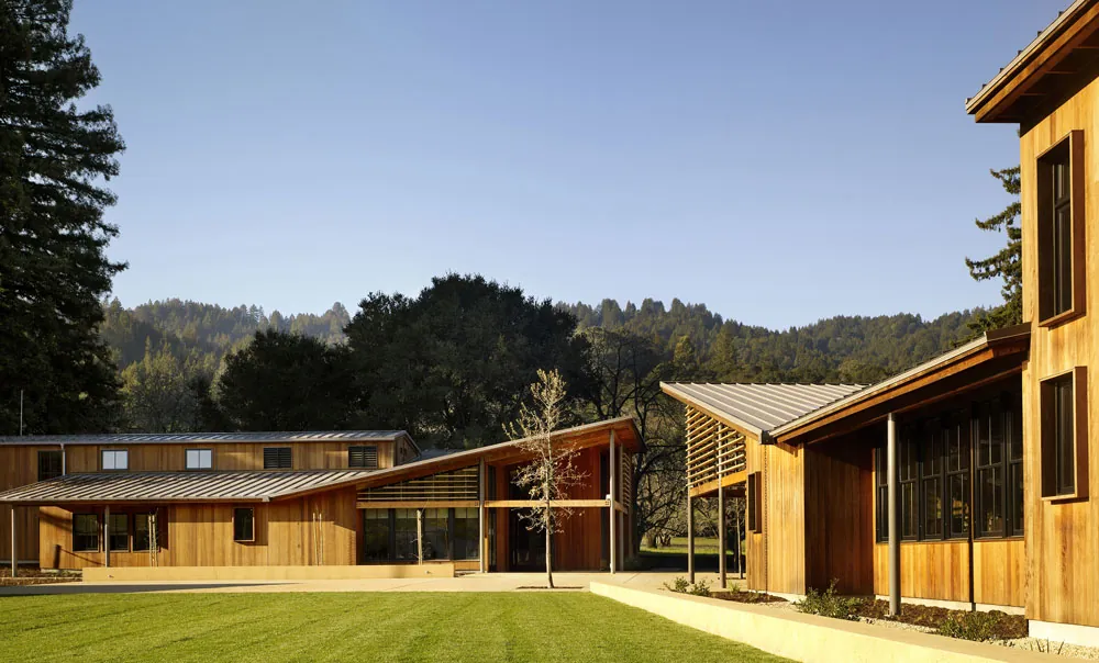 Portola Valley Town Center, Portola Valley, California - cedar-clad civic buildings with standing-seam shed roofs around the lawn, redwood hills behind