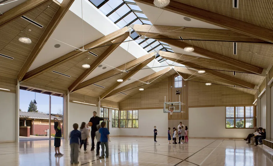 Yountville Town Center & Library, Yountville, California - children playing basketball in the gymnasium beneath exposed glulam trusses and a ridge skylight
