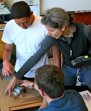 Architect and colleagues reviewing a small scale model at a worktable