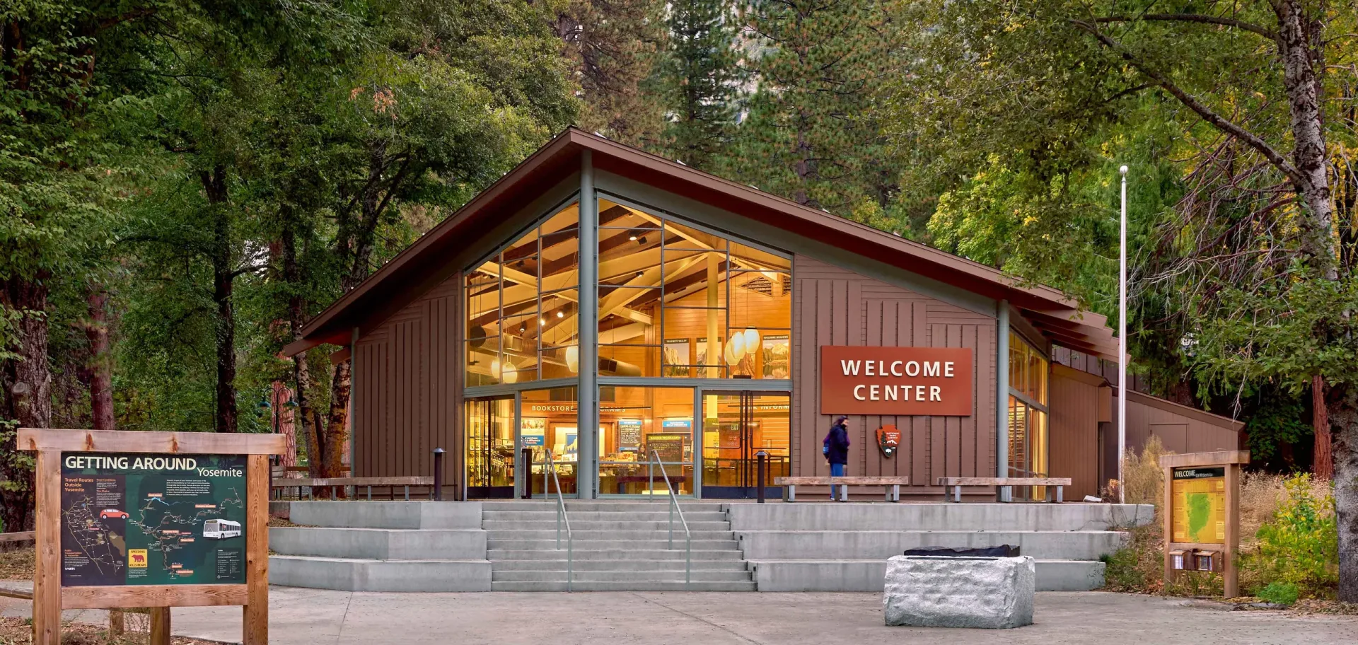 Yosemite Valley Welcome Center, Yosemite National Park, California - timber and glass visitor center glowing at dusk beneath the forest canopy